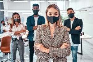 Front view of business people wearing protective masks in the office during the quarantine period